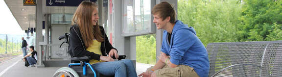 young girl in a wheelchair on the platform with a teen-aged boy