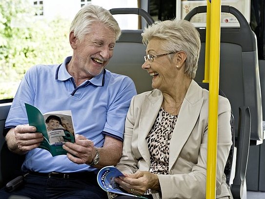 Älteres Paar sitzt lachend im Bus