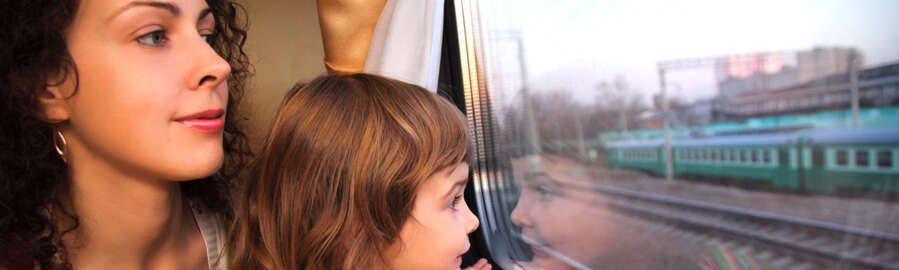 Young woman and a young girl are looking out of a train window