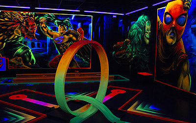 Vergrößerte Ansicht: Rampe in Neonfarben geht durch einen Looping, buntbemalte Wände im Hintergrund