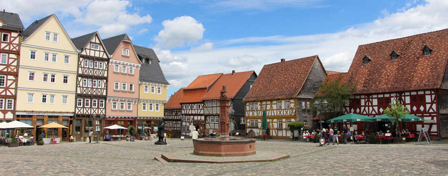 Bunte Fachwerhäuser bilden einen Marktplatz mit Brunnen in der Mitte