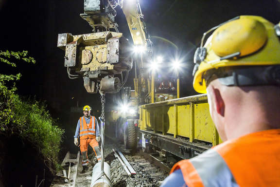 Entladung eines Bauzuges bei Scheinwerferlicht Zwei Arbeiter bei der Entladung eines Bauzuges in der Nacht