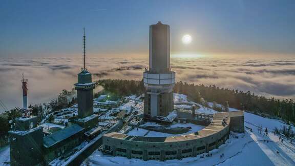 Blick auf einen Aussichtsturm im Schnee über den Wolken