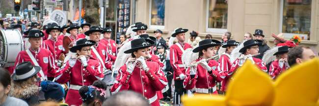 Ein rot gekleideter Spielmannszug zieht an Fastnacht durch die Straßen