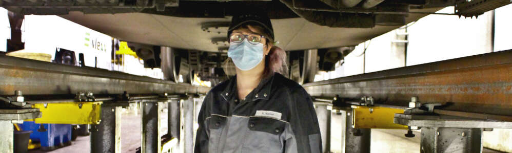 Frau in Arbeitsklamotten in der Arbeitsgruppe unter einem Zug