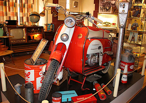 Rot-weißer Motoroller, im Hintergrund Musiktruhe, Jukebox und Vitrine mit Elvis-Exponaten