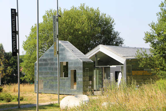 Vergrößerte Ansicht: Außenansicht Besucherzentrum mit silberner Fassade und Dach im Grünen