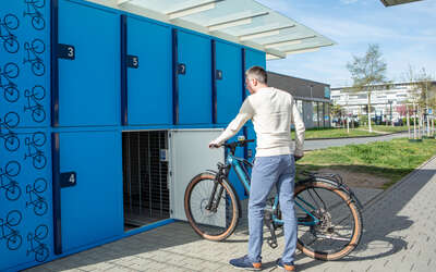 Ein Mann schiebt ein Fahrrad in die Fahrradbox.