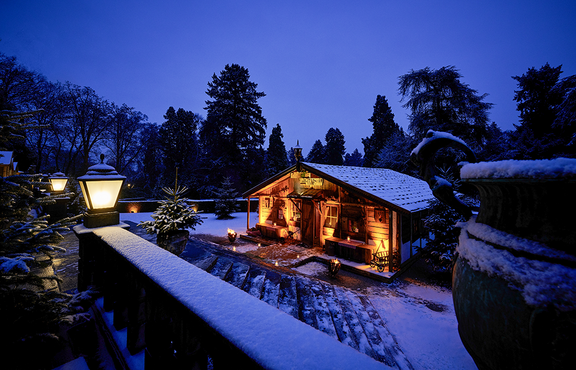 Eine beleuchtete Hütte um die herum Schnee liegt