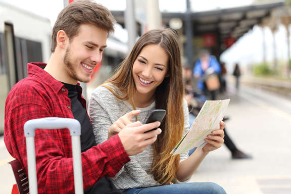 a young couple looking on a mobile phone sitting on the platform