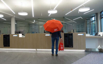 Eine Frau mit rotem MTV-Regenschirm steht vor dem Tresen der Mobilitätszentrale