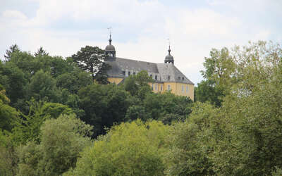 gelbes Schloss hinter Baumwipfeln