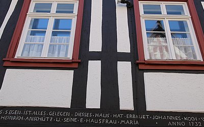 Vergrößerte Ansicht: Spruch an einer Fassade unter zwei Fenstern