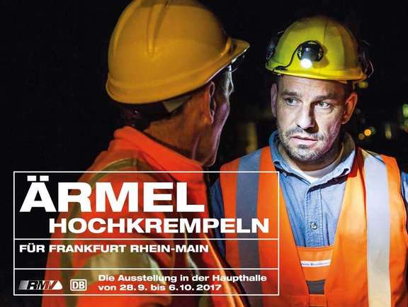 Titelfoto der Ausstellung: Großaufnhame zweier Bauarbeiter im Vordergrund vor erleuchteten S-Bahn-Tunnel