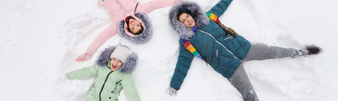Eine Frau und zwei Kinder liegen im Schnee