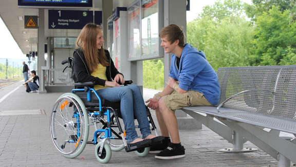 young girl in a wheelchair on the platform with a teen-aged boy