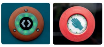 Nahaufnahme: links, runder Taster mit zwei entgegengesetzten Pfeilen in grünen Lichtpunkten. rechts, runder orangener Taster mit Handsymbol innen 