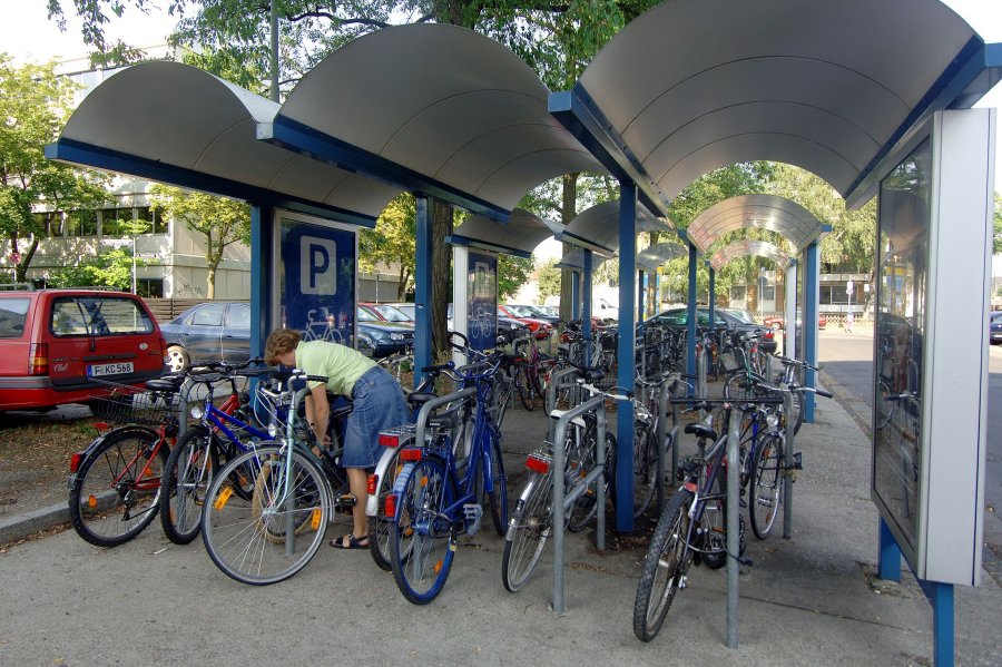 Frau schließt Fahrrad an Fahrradständer an