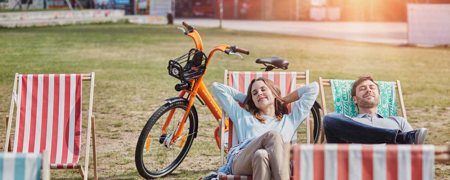 Zwei Personen auf Liegestühlen und ein Fahrrad