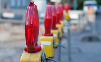 Das Bild zeigt Absperrschranken mit roten Lampen einer Straßenbaustelle.