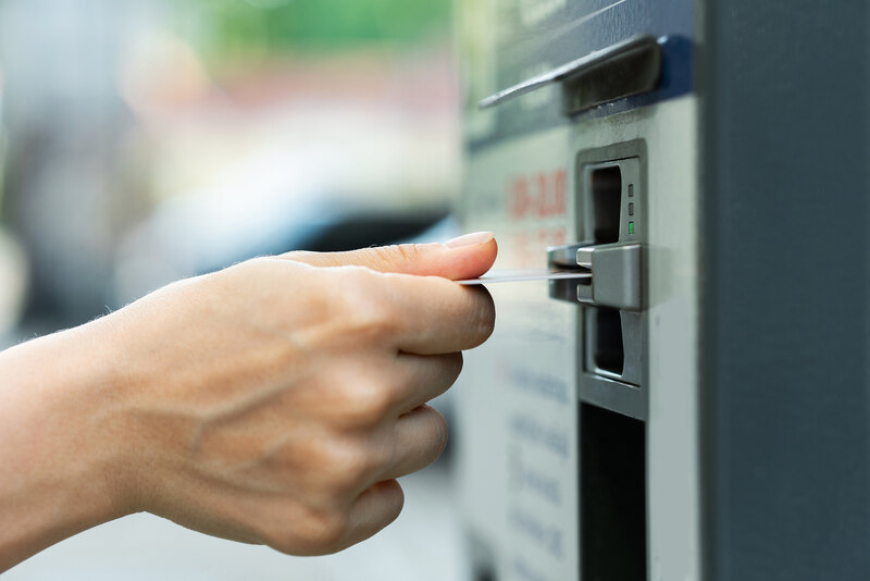 Hand steckt Karte in Fahrkartenautomat
