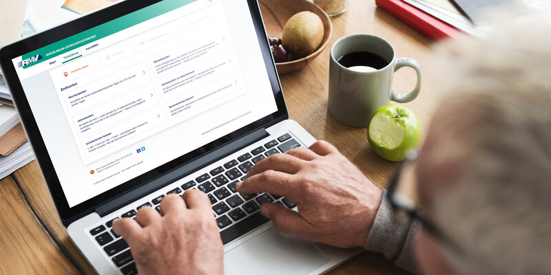 Senior tippt auf Laptop mit RMV-TicketShop auf dem Bildschirm.