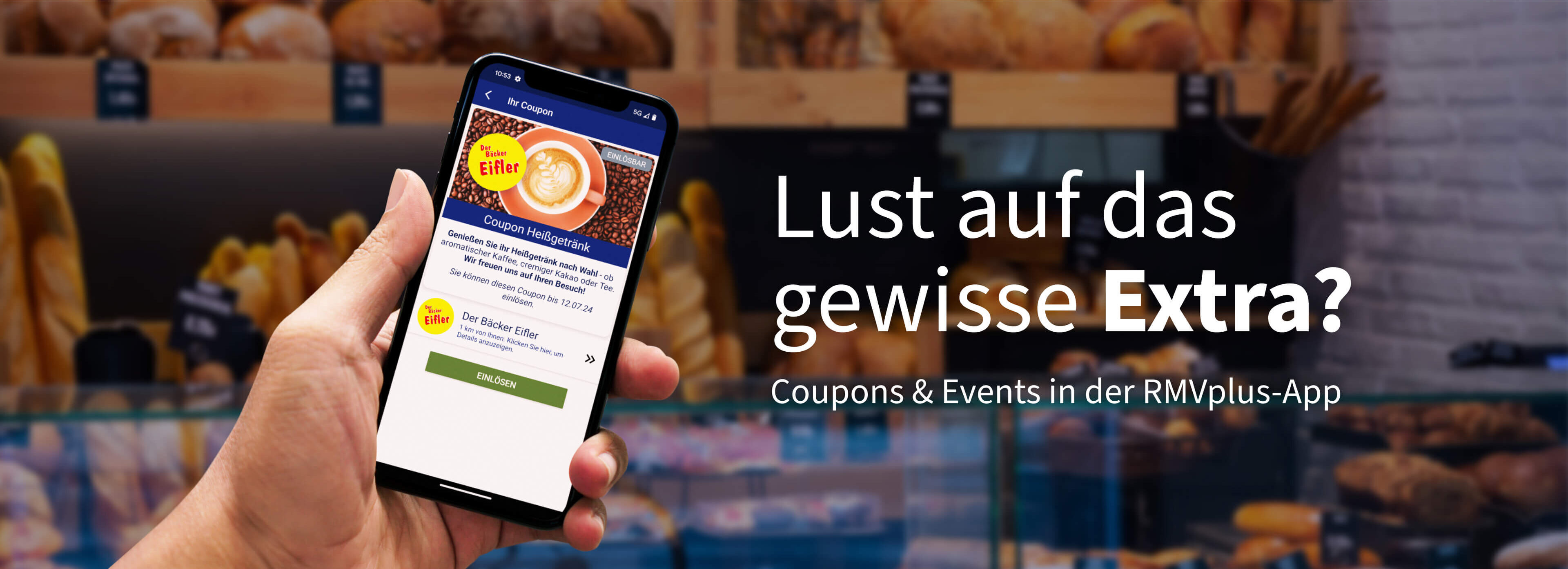 Handy in der Hand zeigt einen Coupon in der App RMVplus vor einer Bäckerei